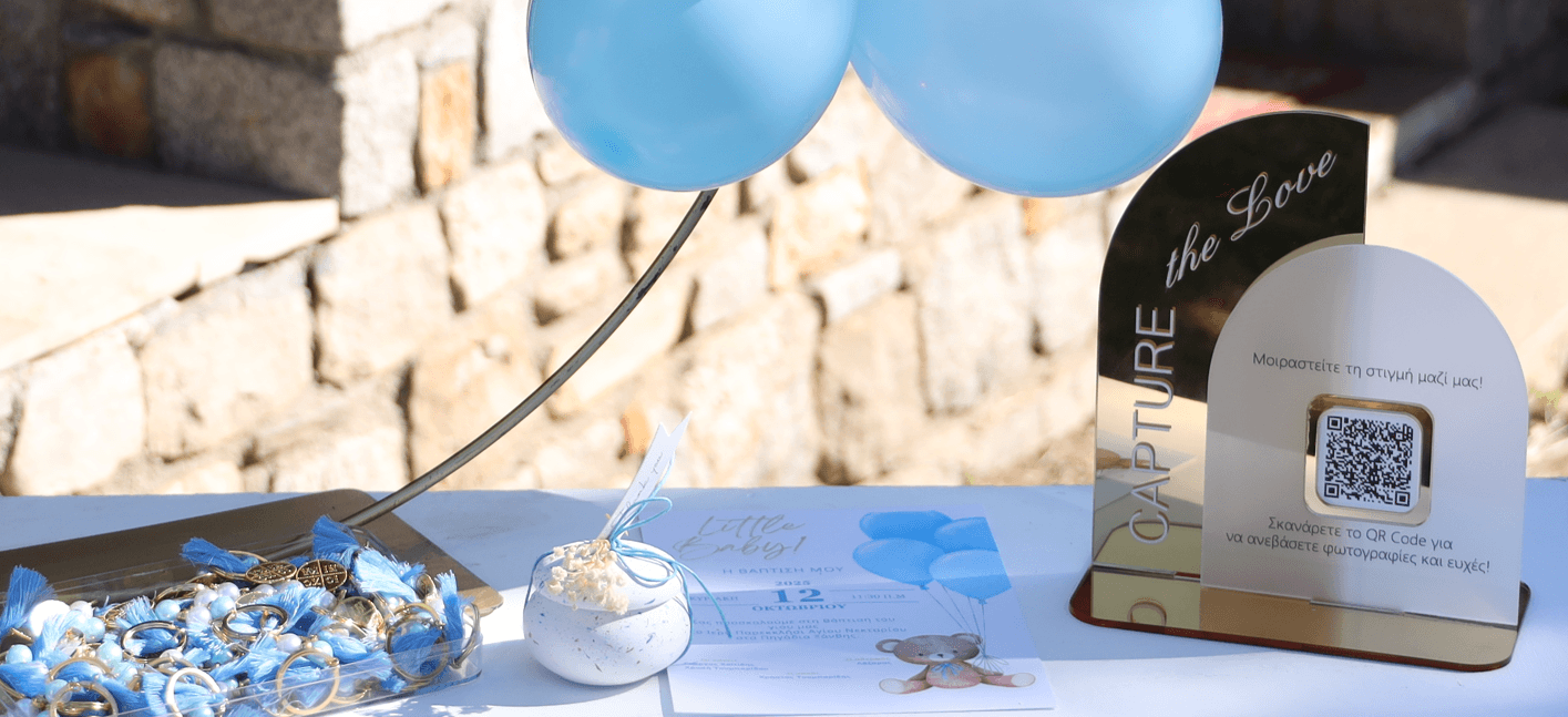 Τραπέζι βάπτισης με μπλε μπαλόνια, μαρτυρικά και το QR stand του Wishbook που γράφει Capture the Love